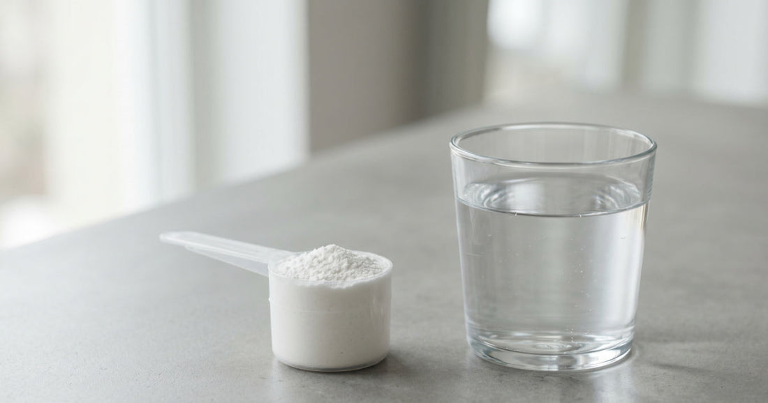 Scoop of creatine monohydrate beside a glass of water